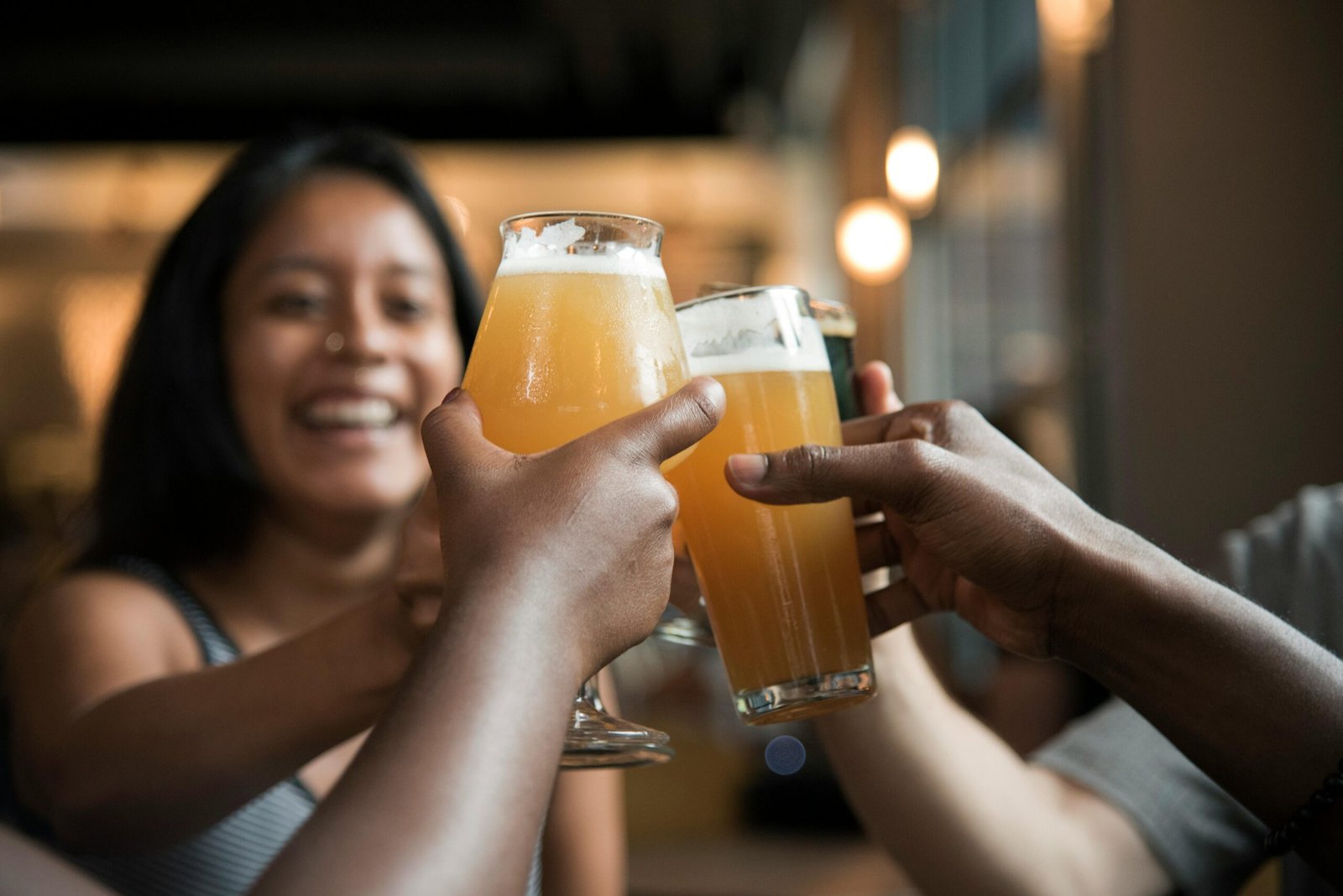 Friends enjoying drinks and toasting in a lively indoor bar setting.