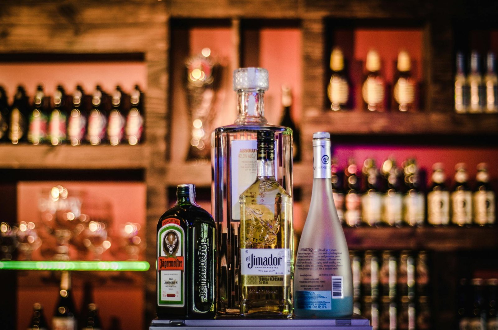 A stylish display of various liquor bottles on a bar shelf with a blurred background.